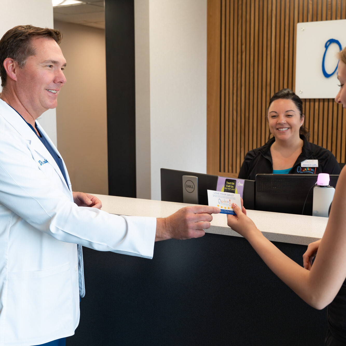 Orthodontist welcoming a patient at the Ovation Orthodontics front desk